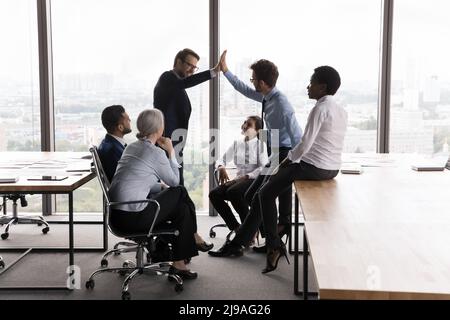 Two colleagues giving high five during briefing in modern boardroom Stock Photo