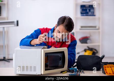 Young repairman repairing oven at workshop Stock Photo