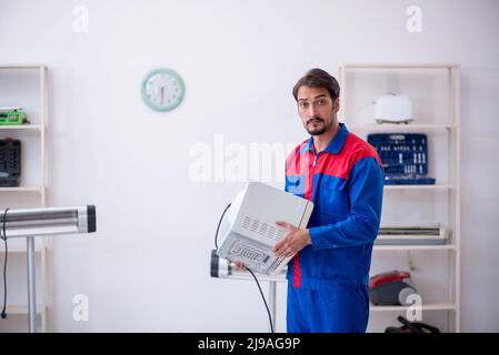 Young repairman repairing oven at workshop Stock Photo