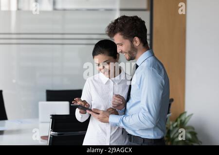 Indian woman with colleague using digital tablet standing in office Stock Photo