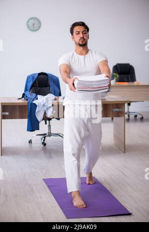 Young businessman employee doing sport exercises at workplace Stock Photo