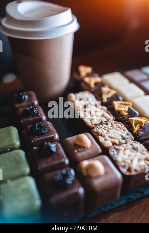 set of delicious handmade chocolate candies with coffee to go in paper cup Stock Photo