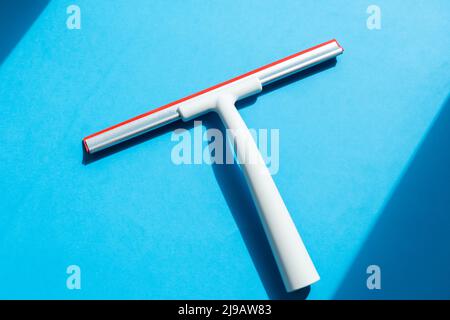 Rubber squeegee for cleaning window on the blue background Stock Photo