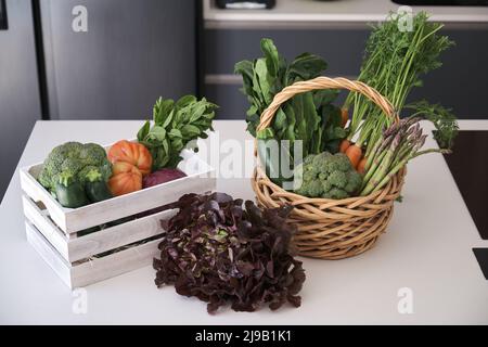 Fresh vegetables basket and box picked in the garden on kitchen table. Stock Photo