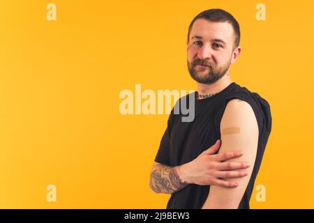 Young European man with plaster on his arm, having tattoos on another arm medium shot copy space studio shot . High quality photo Stock Photo