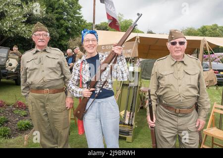 Haworth, West Yorkshire, UK. 22nd May, 2022. Two men dressed as Home Gaurd volunteers instruct a women dressed as a land girl, in rifle use at Haworth1940s weekend. Haworth 1940s weekend is an annual event celebrating the 1940s. Credit: Paul Thompson/Alamy Live News Stock Photo