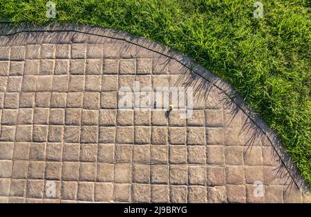 Stamped concrete pavement cobblestones pattern, decorative paving cobblestones tile on cement flooring in a park with green lawn Stock Photo
