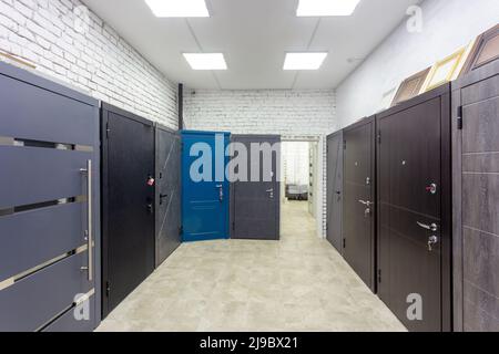 Entrance doors for sale in a specialized store. Buyers prefer metal doors, stylized as wooden. Stock Photo