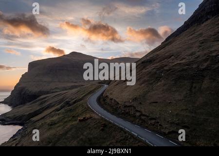 An aerial view shows a road passing through stunning textured landscapes in the Faroe Islands. Stock Photo