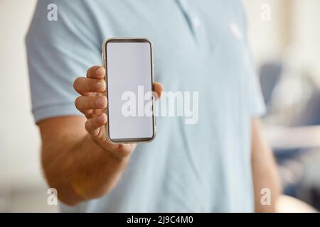 Minimal close up of unrecognizable man holding smartphone with blank screen to camera, copy space Stock Photo