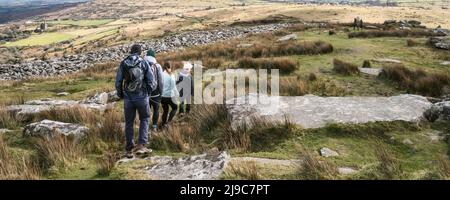 A panoramic image of a group of walkers walking down Stowes Hill on the rugged Bodmin Moor in Cornwall in the UK. Stock Photo