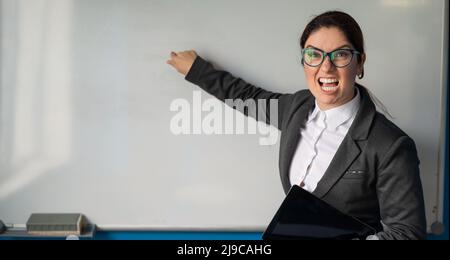 Angry business woman coach points finger to white board in office.A ...