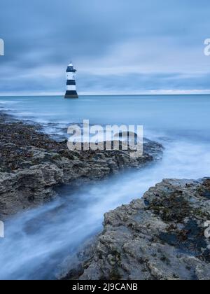 The lighthouse at Penmon Point on Anglesey with waves washing over the foreground. Stock Photo
