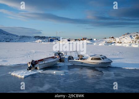 Fishing boats at the edge of the sea ice in Oqaatsut harbour in west Greenland. Stock Photo