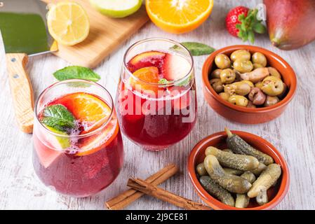 Two glasses with sangria, a typical Spanish drink, accompanied by some olives and pickles in vinegar. In the background. Stock Photo