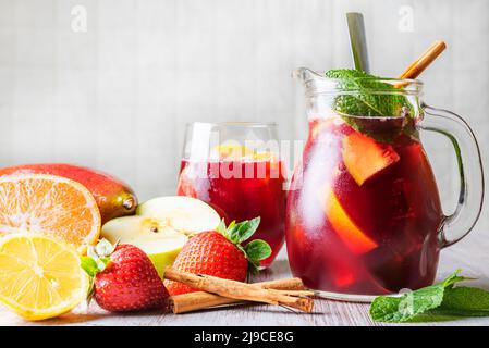 Pitcher and glass with sangria, a typical Spanish drink, along with the fruits used in its preparation. Stock Photo