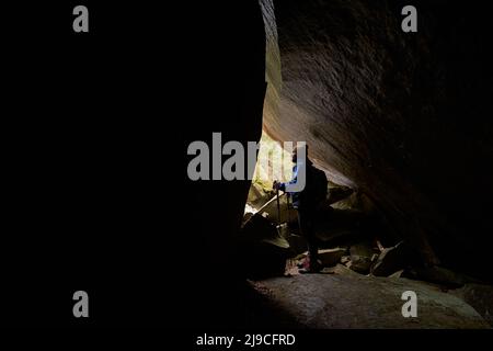 Thoughtful male looking at view through crack in rock Stock Photo