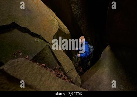 Positive delighted hiker standing in crack of rock Stock Photo