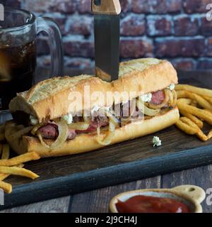 Freshly made steak hoagie bun with blue cheese and onions, served with fries. Stock Photo