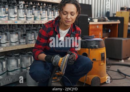 Young auto mechanic preparing grinding machine for work Stock Photo