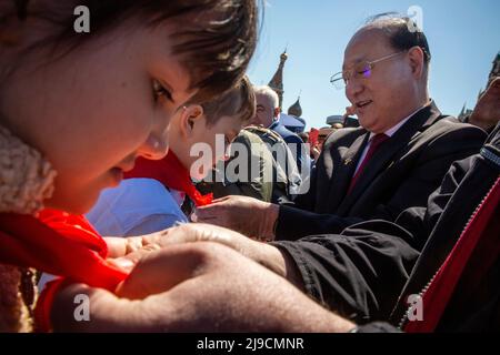 Moscow, Russia. 22nd May, 2022. North Korean Ambassador Sin Hong-chol (R) ties a red neckerchiefs for a boy as he joins the Young Pioneers on Red Square during a ceremony to celebrate joining the Pioneers organization and 100th anniversary of the All-Union Pioneer Organization, in Moscow, Russia. Nikolay Vinokurov/Alamy Live News Stock Photo