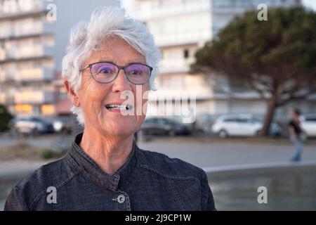 Portrait of an elderly person with glasses and white hair in town Stock Photo