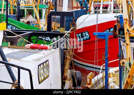 Close up detail of a busy scene at Arbroath harbour, with several colourful fishing boats docked at the quayside. Stock Photo