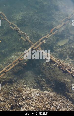 Rusted anchor chain in deep blue ocean connecting surface vessel to ...