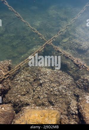 Rusted anchor chain in deep blue ocean connecting surface vessel to ...