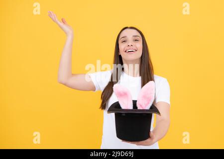 Happy woman in easter bunny ears. Rabbit ears appear from the magic hat. Stock Photo