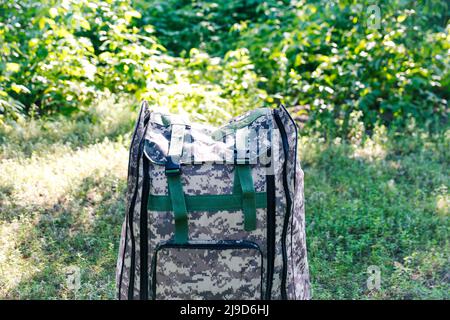 Defocus military backpack. Army bag on green grass background near tree. Military camouflage webbing material on a British army rucksack. Closeup. Tou Stock Photo