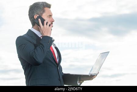 businessman in suit speaking on phone and hold laptop Stock Photo