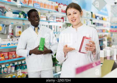 Portrait of two pharmacists offering medication in modern pharmacy Stock Photo