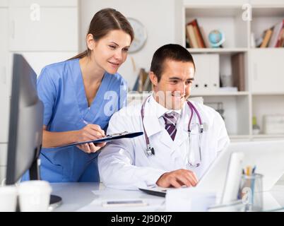 Two physicians working with case histories on laptop Stock Photo