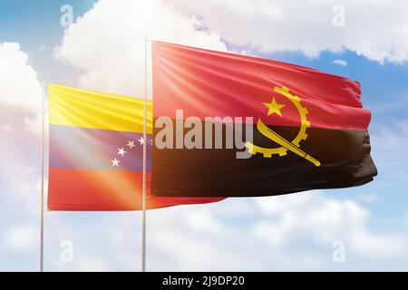 Venezuela and Angola flags waving together in the wind on blue cloudy ...