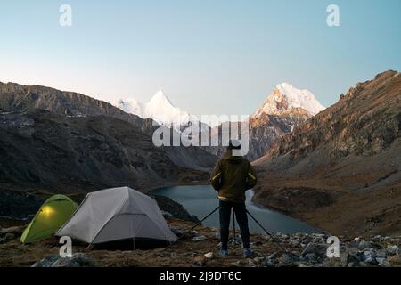 asian camper photographer taking a picture of mountain and lake in yading national park, daocheng county, sichuan province, china Stock Photo