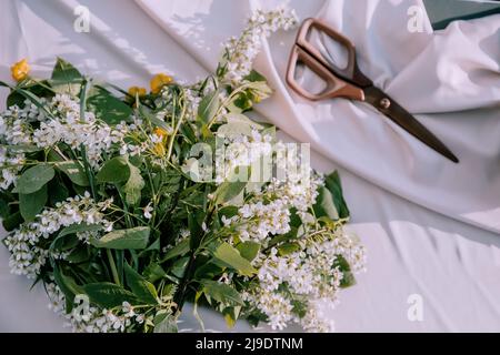 The florist desktop with working tools on light sunny background, Floristic tools like scissors, secateurs, twine, knife, flowers Stock Photo