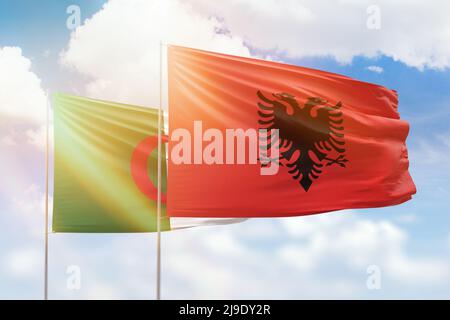 Sunny blue sky and flags of albania and algeria Stock Photo