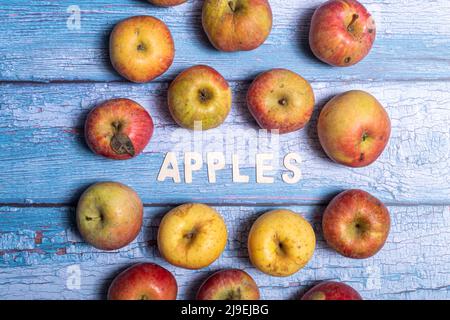 Yellow and red tasty apple fruit with apples word written won wooden letters on a blue wooden board Stock Photo