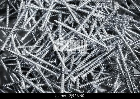 Pile of shiny new self-tapping screws, close-up background photo with selective soft focus Stock Photo