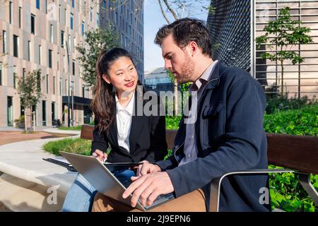 woman and man working with laptop in a park Stock Photo