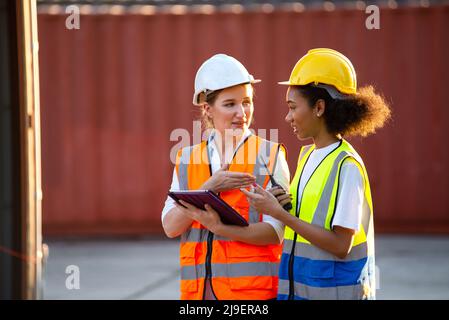Businesswoman and logistics woman worker checking containers box and loading products in computer  from Cargo freight ship at Cargo container. Stock Photo