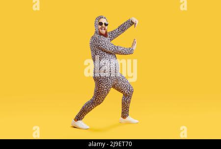 Funny cheerful fat guy wearing crazy leopard PJs dancing and having fun in fashion studio Stock Photo