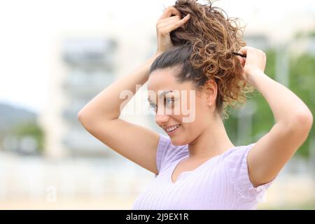 Happy woman doing ponytail walking in the street Stock Photo