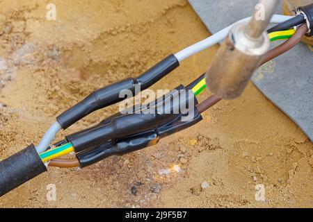 Heat-shrink tubing over underground cables is shrunk with a gas flame Stock Photo