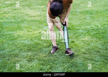 Young man adjusting his prosthetic leg outdoor - Focus on hand holding prosthesis Stock Photo