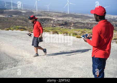 Multiracial engineer men working on a windmill farm drone - Focus on african man hands holding tablet Stock Photo