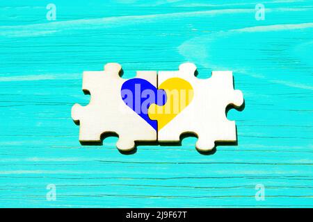 Heart symbol made from jigsaw puzzle pieces painted the colors of the national flag of Ukraine. Stock Photo