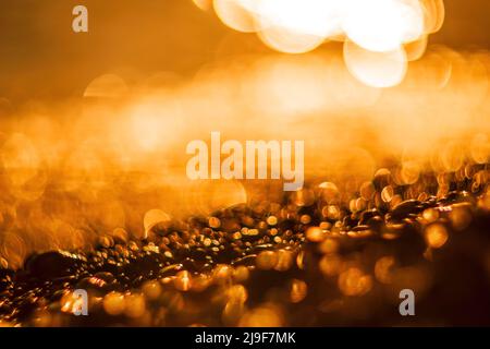 Abstract nature summer ocean sunset sea background. Small waves on water surface in motion blur with bokeh lights from sunrise. Holiday, vacation and Stock Photo