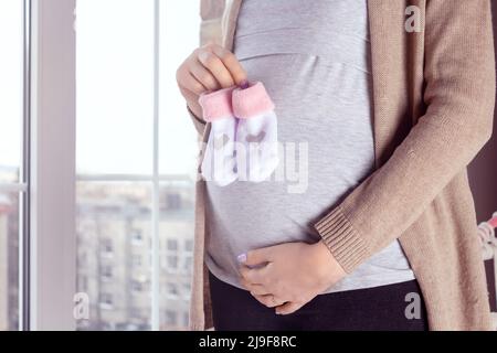 Pregnant woman by the window. Close up. Stock Photo